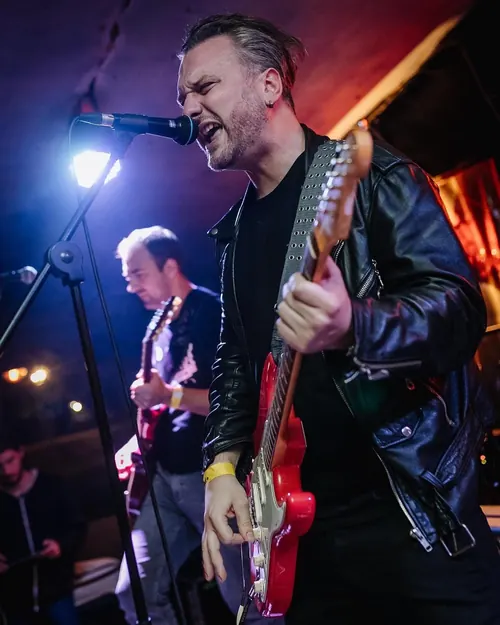 Gitarista u kožnoj jakni peva na bini