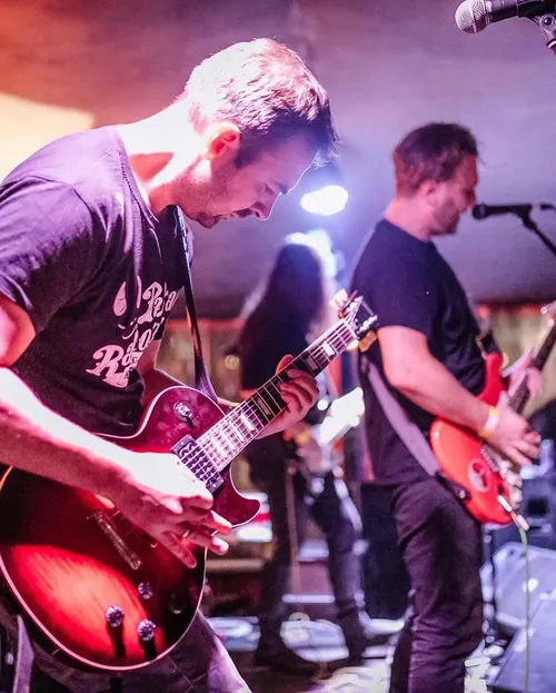 Gitaristi na bini u plavom i crvenom svetlu